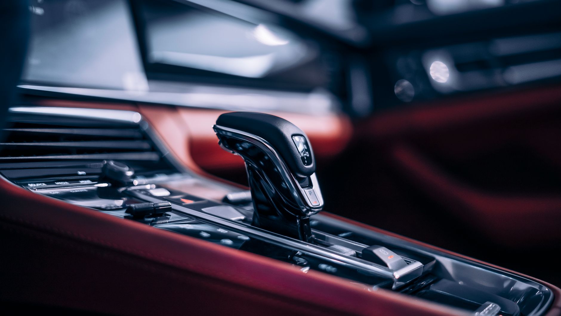 Close-up of a gear shift and controls inside a car interior in low light