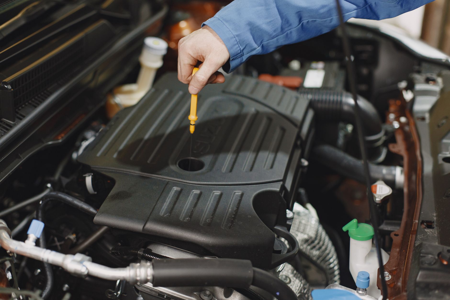 A hand pulling the dipstick to check engine oil, the simplest habit that saves the dearest repair