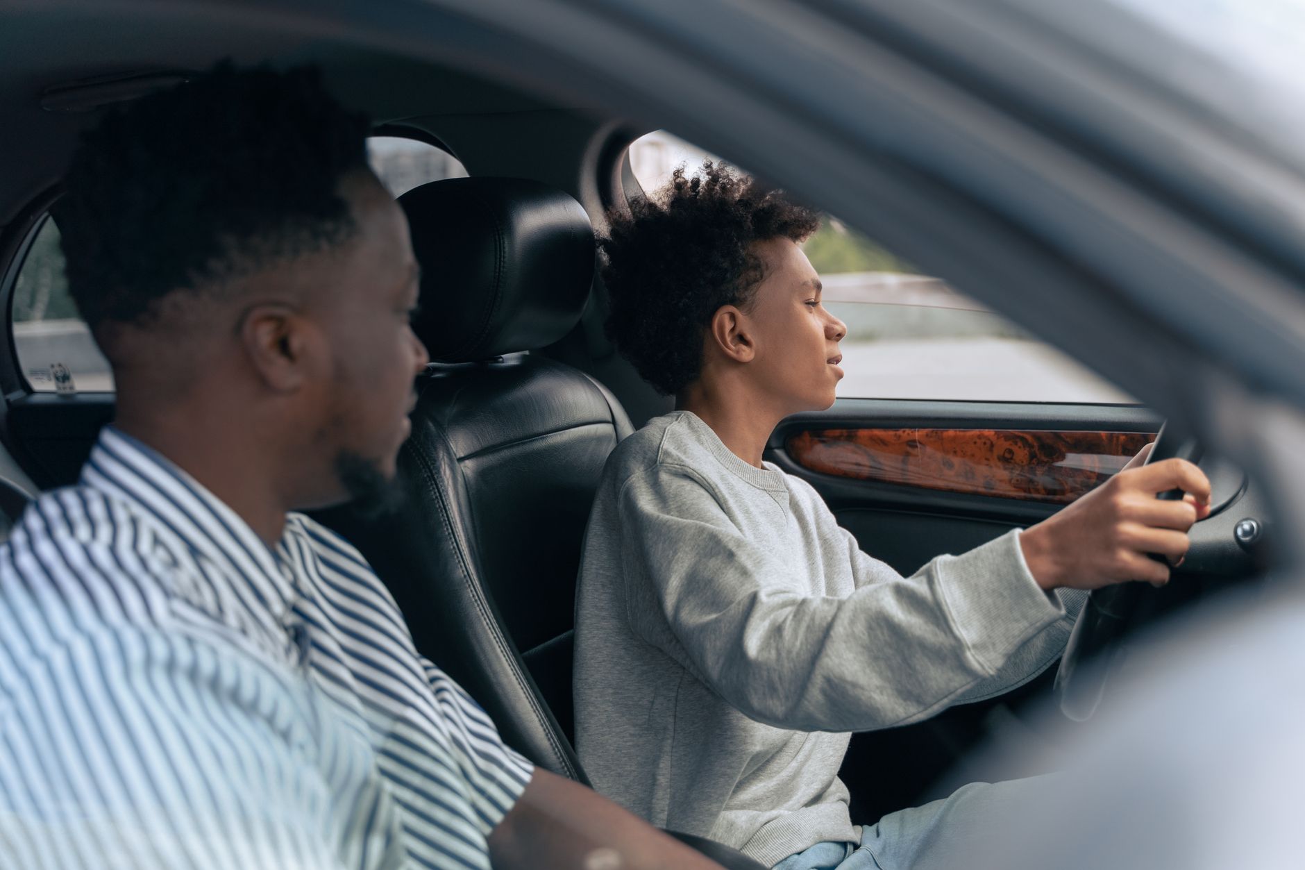 A parent guiding a learner driver through an early practice session from the passenger seat