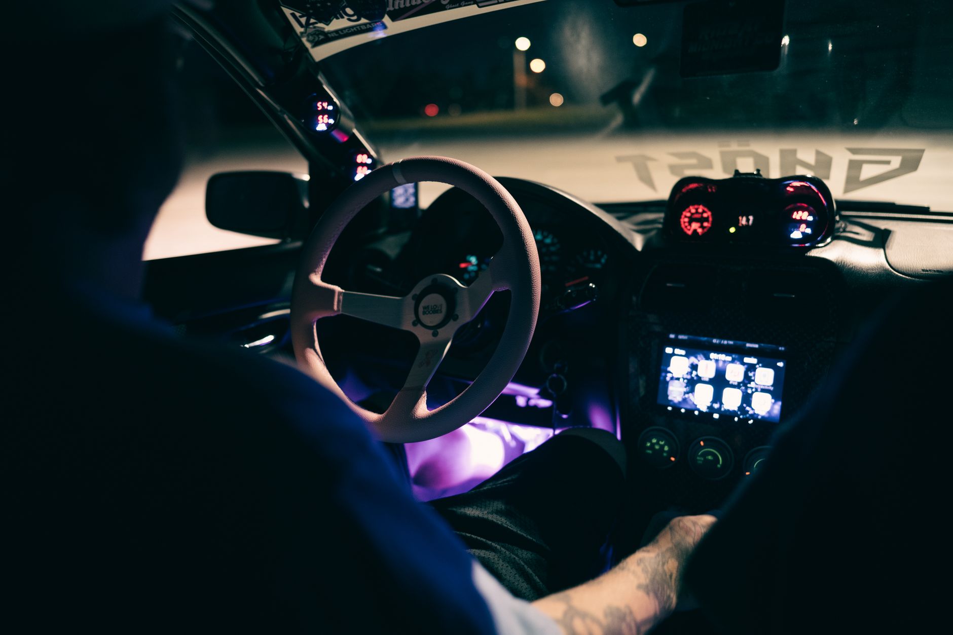 A driver's hands on the wheel with the dashboard lit at night, the view a working driver actually has