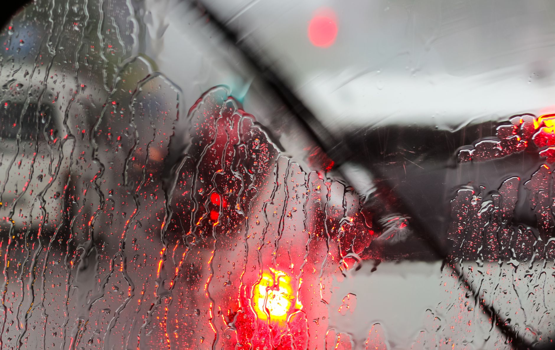 Rain running down a windscreen with brake lights smeared beyond it, the exact moment good anticipation earns its keep